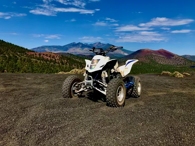 A white and blue atv parked on top of a dirt field.